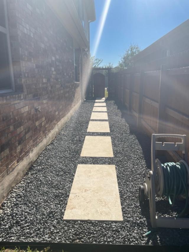 Side yard pathway with stone pavers and garden hose