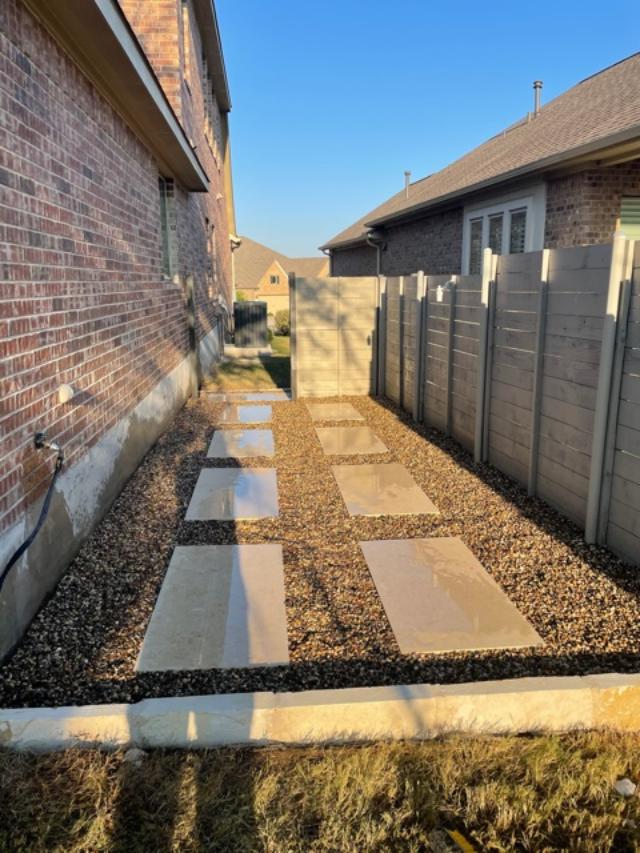 Side yard with stone pavers and concrete fence
