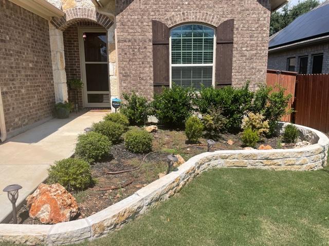 Front yard with curved stone retaining wall and plants